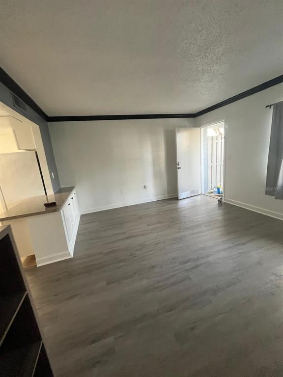 An open-concept living area features gray wood-look flooring, white walls, and a kitchen breakfast bar — 131 WATER FRONT WAY UNIT 150, ALTAMONTE SPRINGS, FL