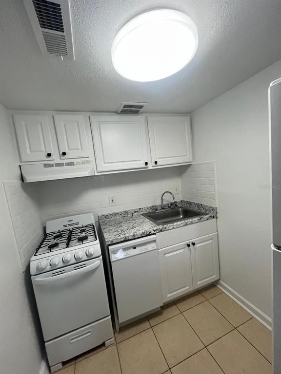 A small kitchen features white cabinets, granite countertops, a gas stove, and a dishwasher — 131 WATER FRONT WAY UNIT 150, ALTAMONTE SPRINGS, FL