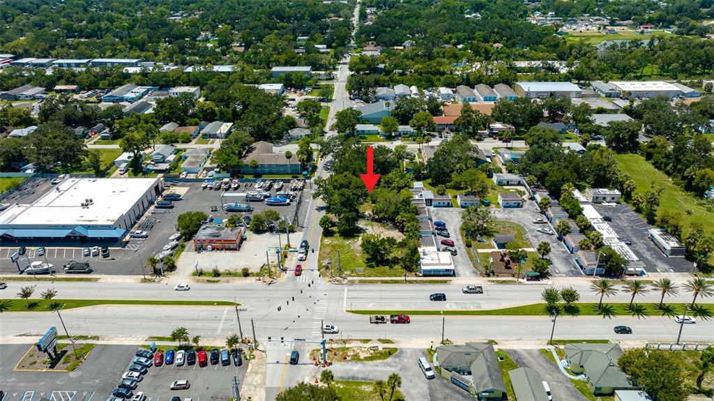 This aerial view shows a vacant lot marked by a red arrow near a road — 000 RIDGEWOOD AVENUE, HOLLY HILL, FL