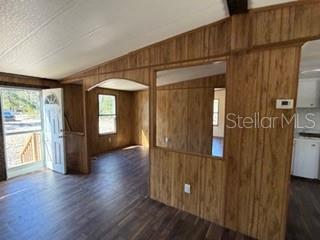 An interior view shows a room with wood-paneled walls, dark flooring, and an arched doorway — 1668 NE 592ND STREET, OLD TOWN, FL