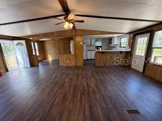 An open-concept living area features wood-paneled walls, dark wood-look flooring, and a kitchen island — 1668 NE 592ND STREET, OLD TOWN, FL