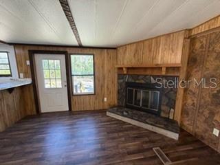 A living room features wood-paneled walls, a stone fireplace, and a white entry door — 1668 NE 592ND STREET, OLD TOWN, FL