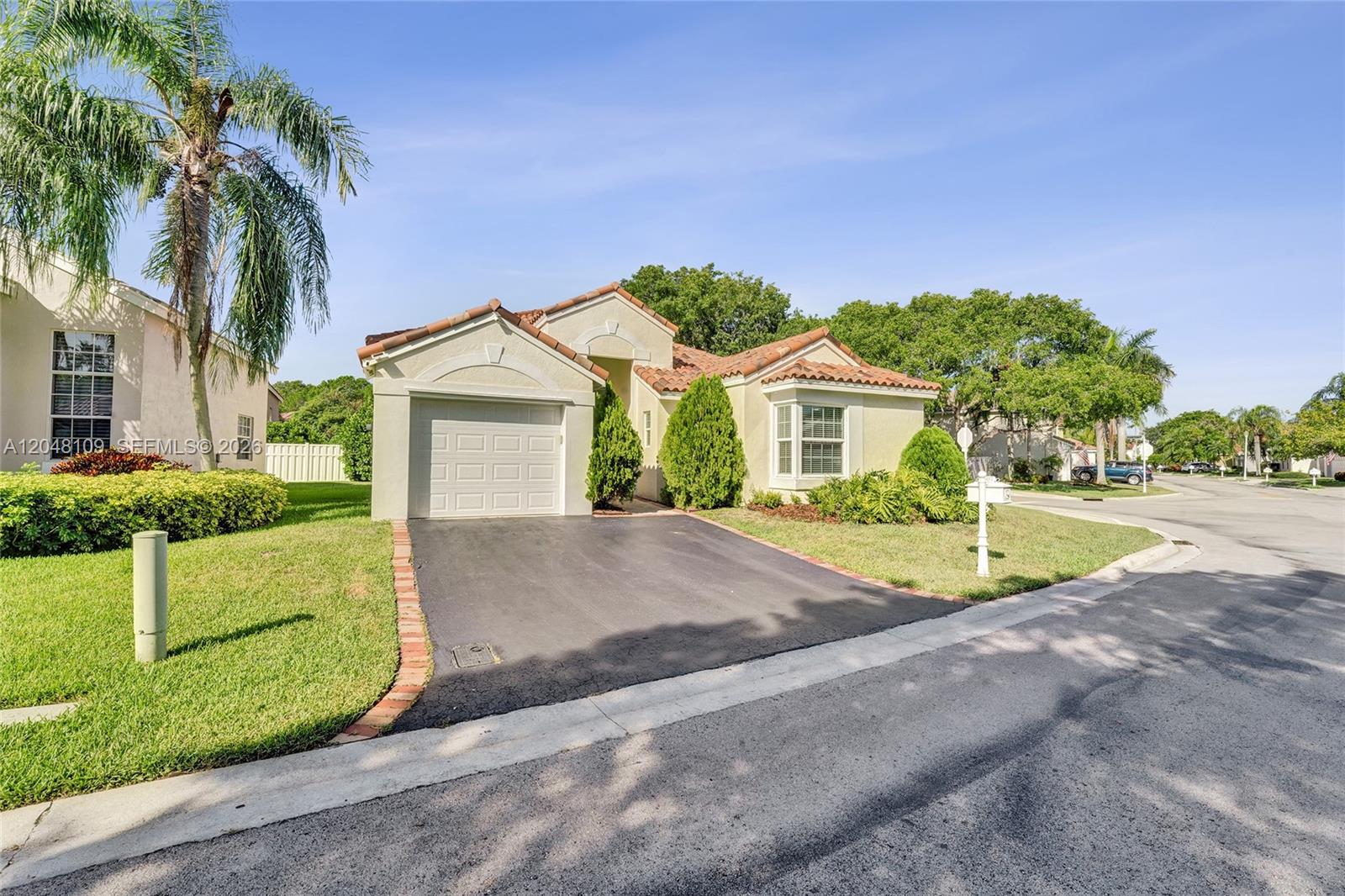 A single-story house with a garage, driveway, and tiled roof sits on a corner lot — 507 Bridgeton Rd, Weston FL 33326, WESTON, FL
