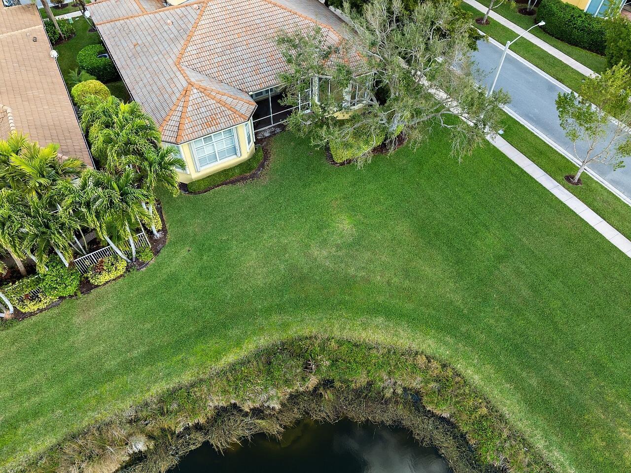 An aerial view shows a house with a tiled roof, palm trees, and a grassy backyard — 9724 Via Grandezza W, Wellington FL 33411, WELLINGTON, FL