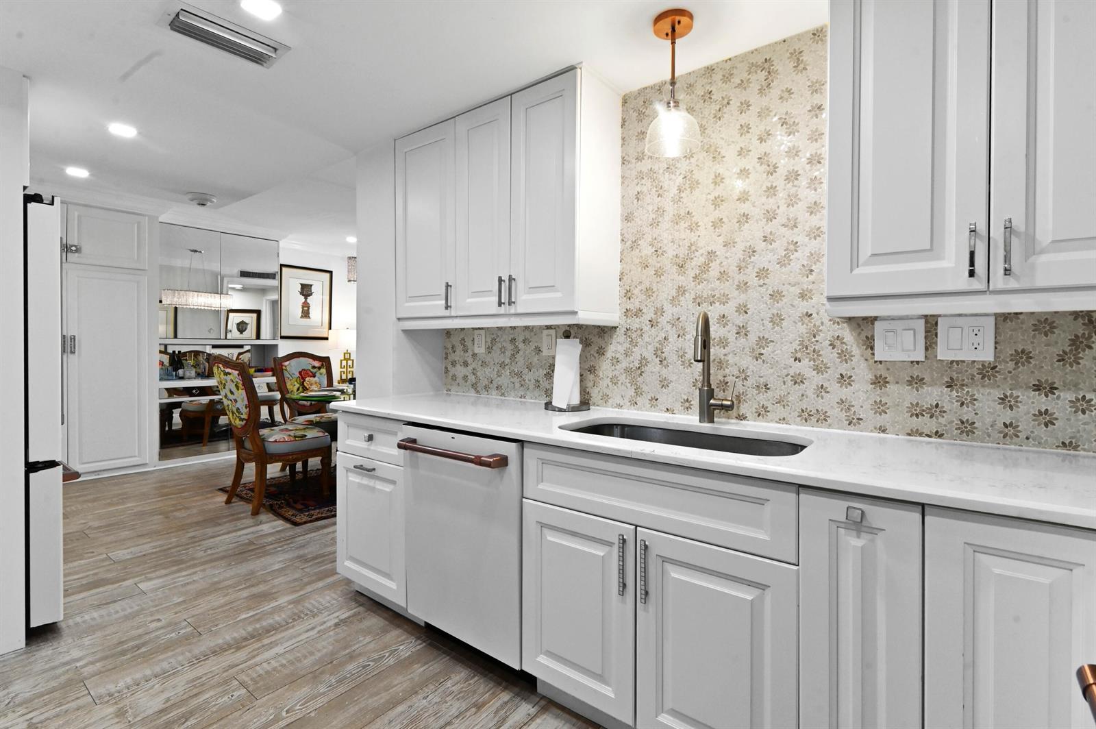 A kitchen with white cabinets, a floral tile backsplash, and a stainless steel sink — 2840 S Ocean Boulevard # 109, Palm Beach FL 33480, PALM BEACH, FL