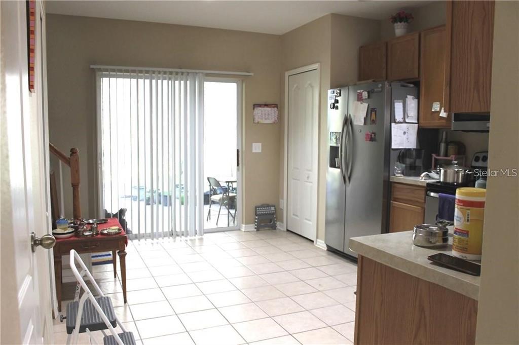 A kitchen with tile flooring, wood cabinets, stainless steel appliances, and a sliding glass door — 5815 FISHHAWK RIDGE DRIVE, LITHIA, FL