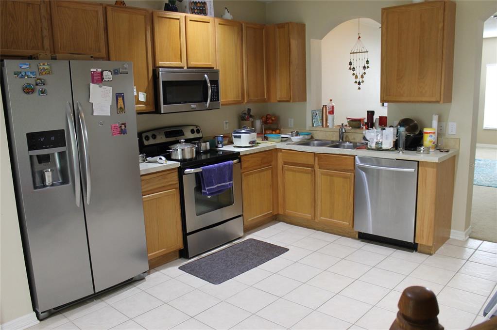 A kitchen with light wood cabinets, stainless steel appliances, and white tile flooring — 5815 FISHHAWK RIDGE DRIVE, LITHIA, FL