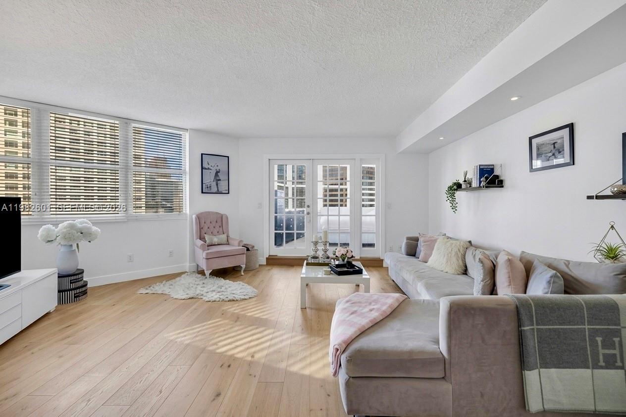 A bright living room features light wood floors, a grey sectional sofa, and glass doors — 801 Brickell Bay Dr # 1262, Miami FL 33131, MIAMI, FL