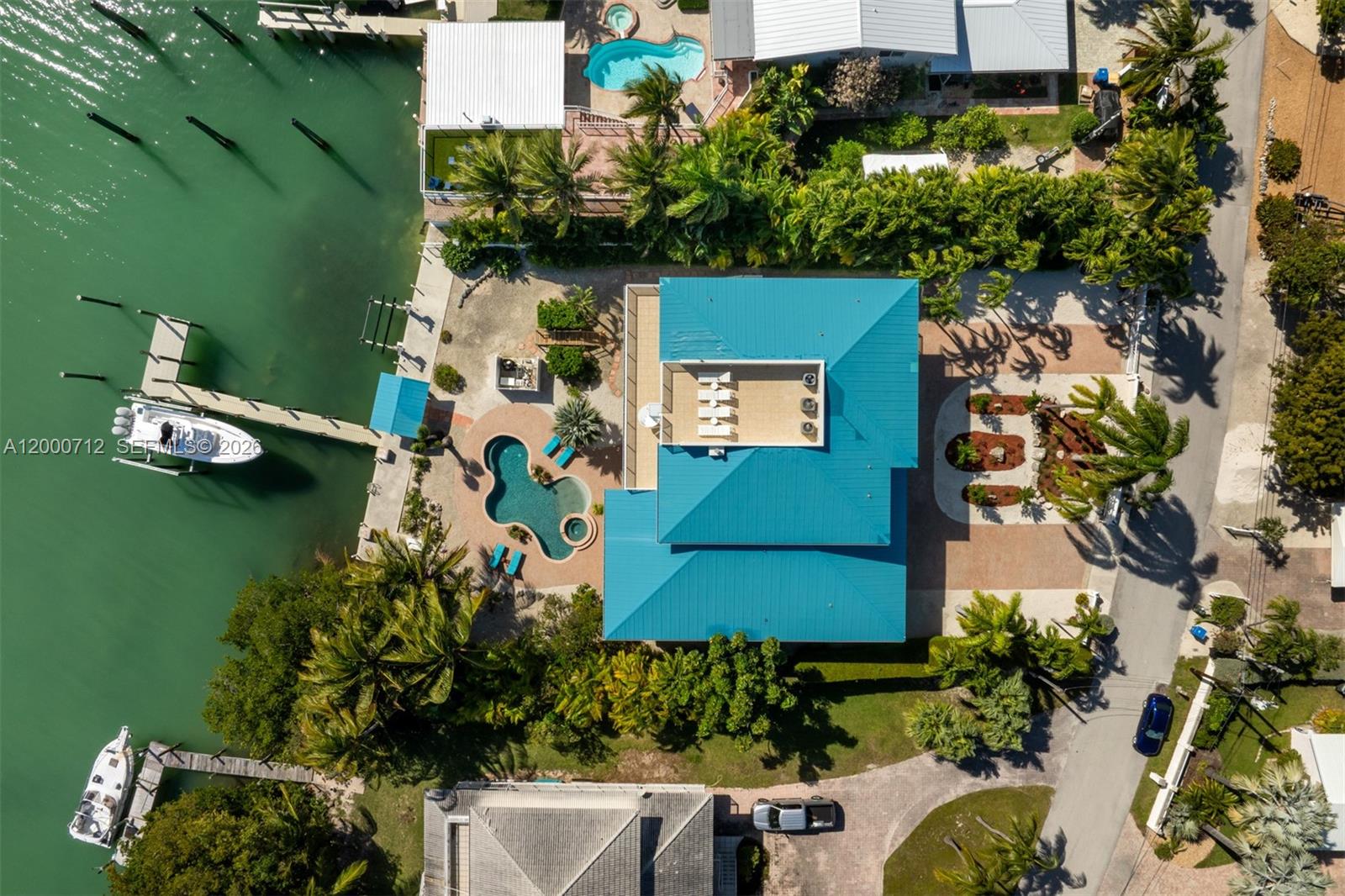 An aerial view shows a waterfront house with a blue roof, pool, and boat dock — 137 Sapodilla Dr, Islamorada FL 33036, ISLAMORADA, FL
