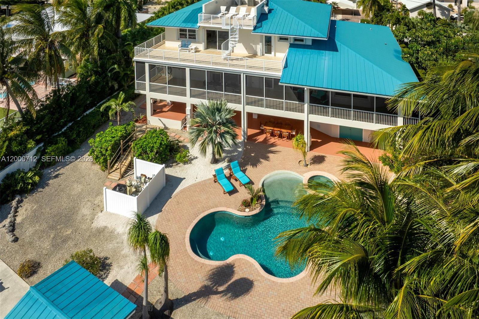 An aerial view shows a multi-story house with a blue metal roof, pool, and palm trees — 137 Sapodilla Dr, Islamorada FL 33036, ISLAMORADA, FL