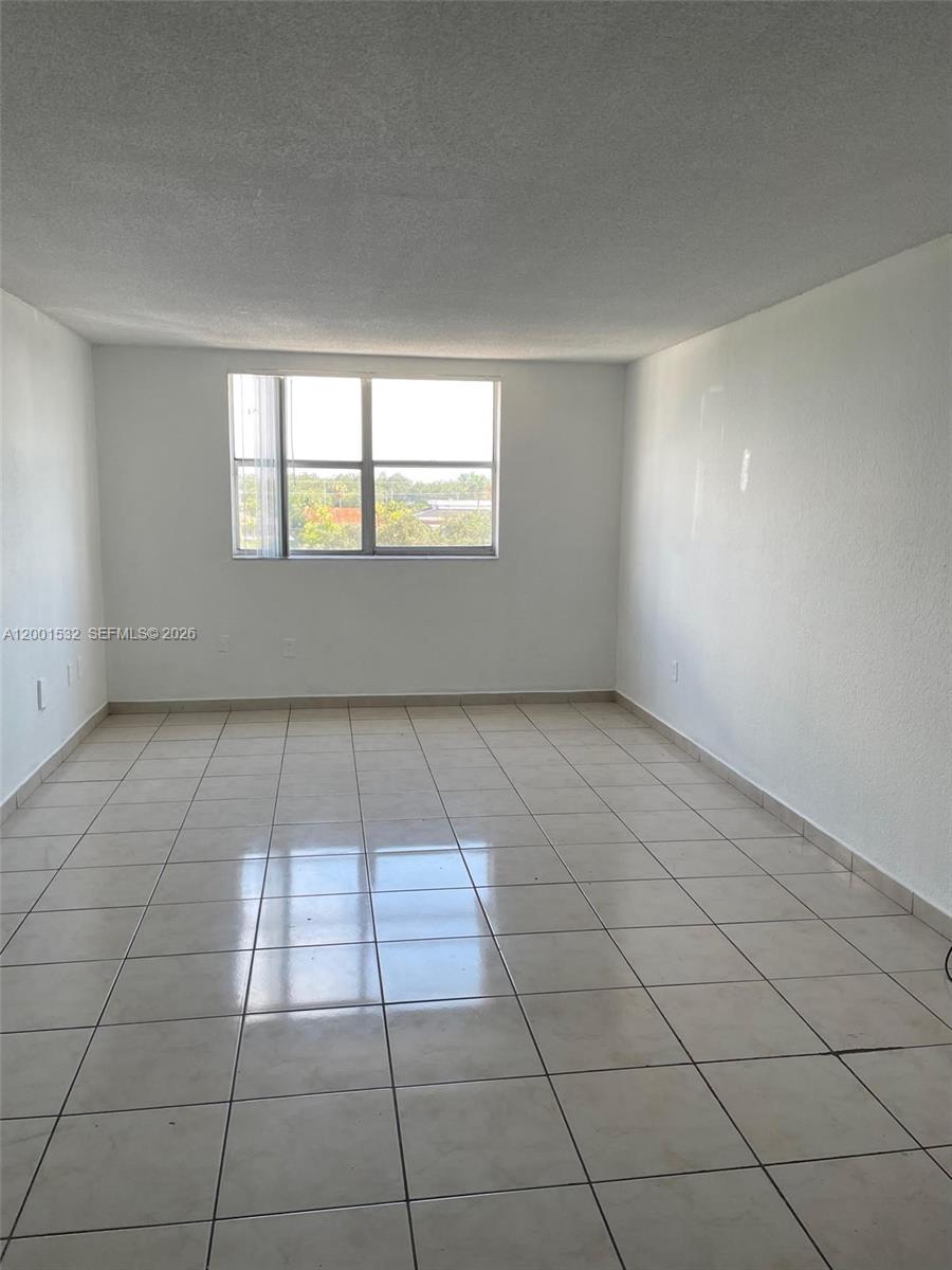 An empty room features white walls, a single window, and light-colored square floor tiles — 666 W 81st St # 407, Hialeah FL 33014, HIALEAH, FL