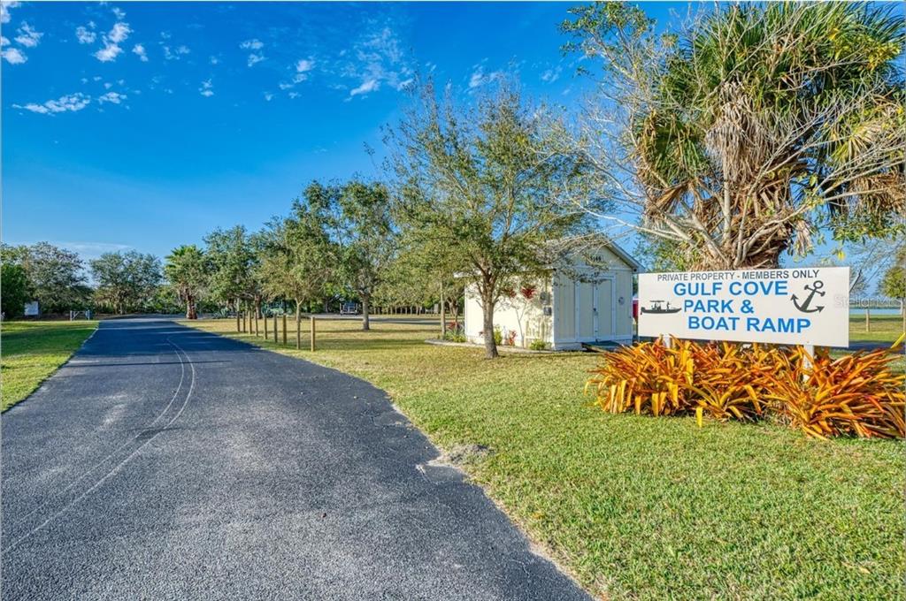 An asphalt driveway leads to a small storage building and a Gulf Cove park sign — 3135 DWYER STREET, PORT CHARLOTTE, FL