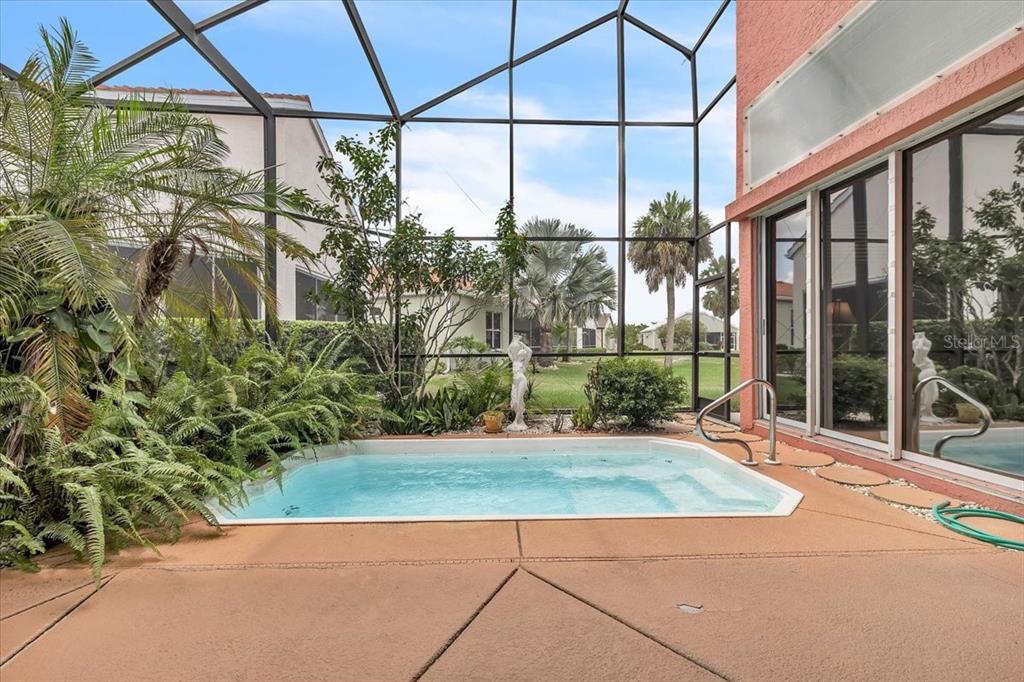 A screened-in patio features a small rectangular swimming pool surrounded by lush tropical landscaping — 10316 ARROWHEAD DRIVE, PUNTA GORDA, FL