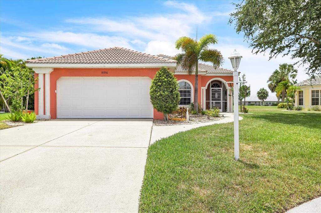 A single-story house with an orange exterior, a two-car garage, and a palm tree — 10316 ARROWHEAD DRIVE, PUNTA GORDA, FL