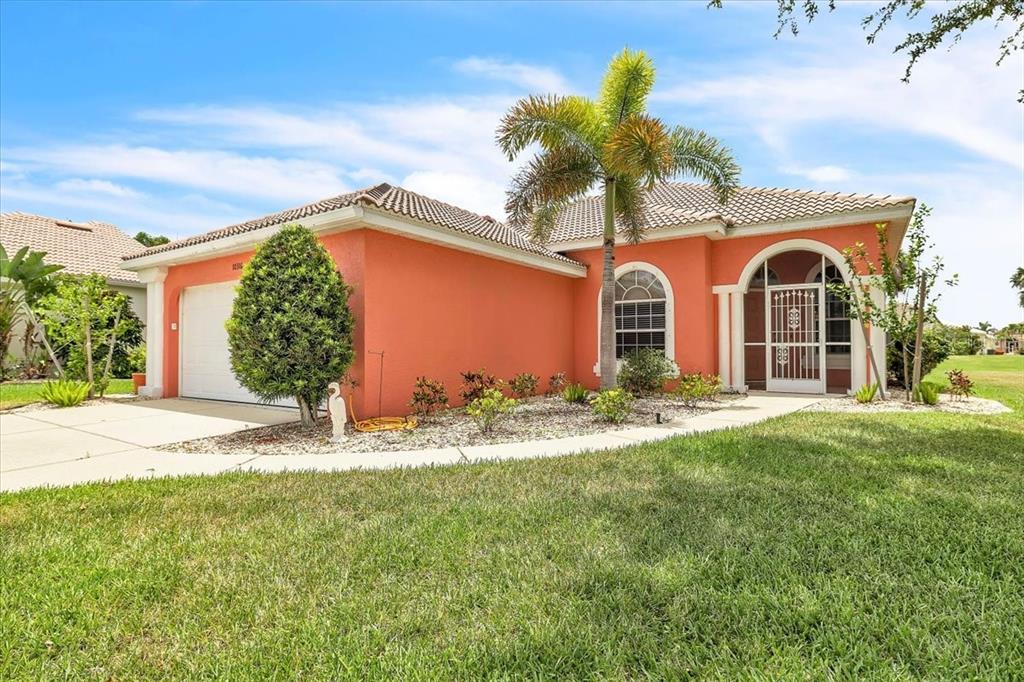 A single-story house with orange stucco walls, a tile roof, and a palm tree — 10316 ARROWHEAD DRIVE, PUNTA GORDA, FL