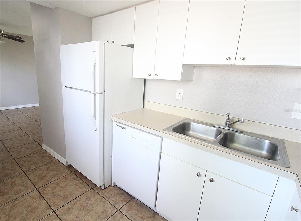 A kitchen with white cabinets, a white refrigerator, a dishwasher, and a double-basin sink — 5310 26TH STREET W UNIT 1502, BRADENTON, FL