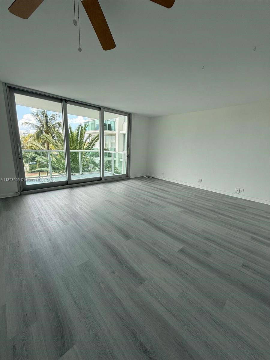 An empty room features light gray wood-look flooring, white walls, and a large sliding glass door — 1000 West Ave # 306, Miami Beach FL 33139, MIAMI BEACH, FL