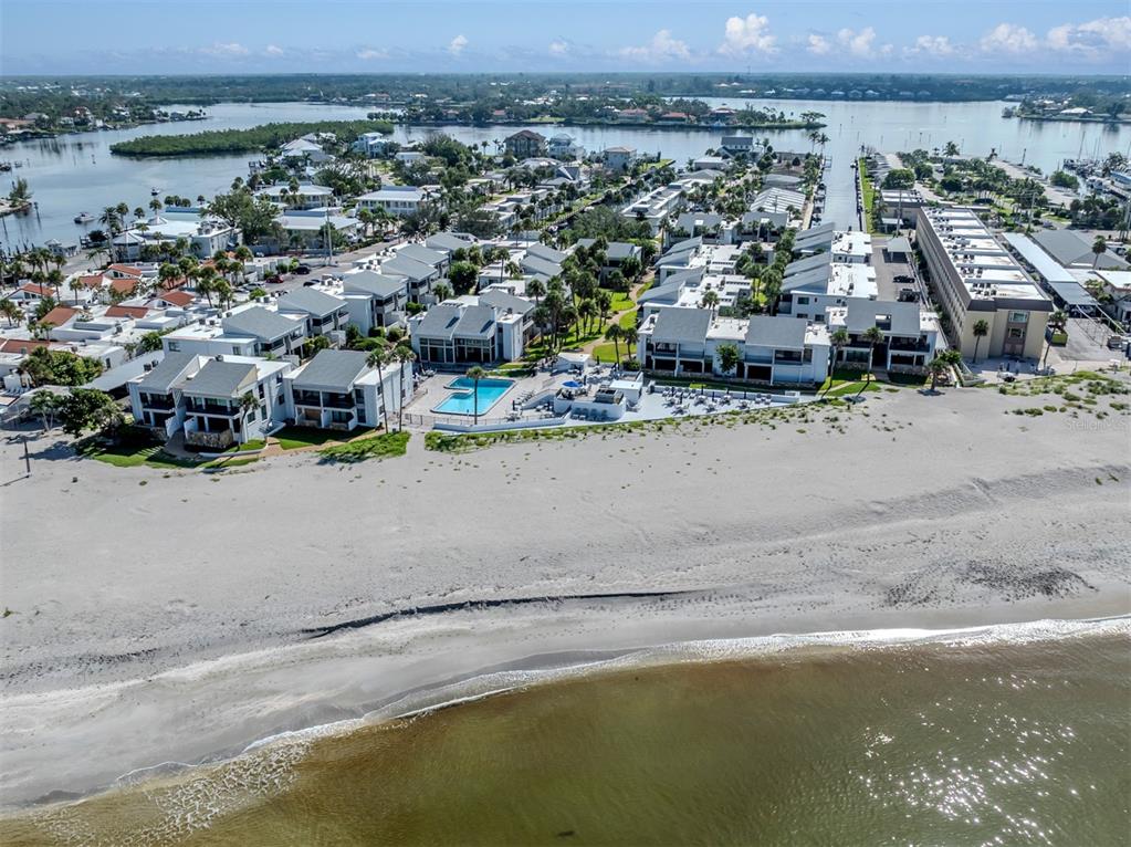 An aerial view shows a beachfront residential complex with a swimming pool and sandy beach — 1555 TARPON CENTER DRIVE UNIT 255, VENICE, FL