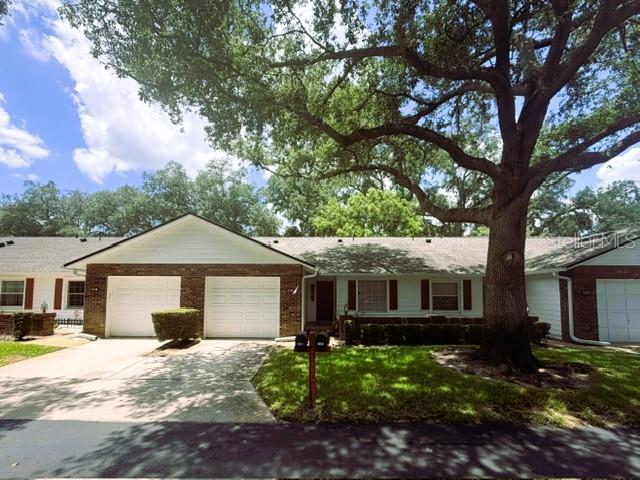 A single-story brick and white siding house with two garage doors and a large tree — 5184 LAZY OAKS DRIVE, WINTER PARK, FL