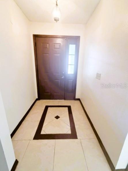 A foyer with a dark brown front door, a pendant light, and decorative tile flooring — 5184 LAZY OAKS DRIVE, WINTER PARK, FL