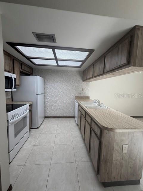 A kitchen features wood-look cabinets, white appliances, a tiled floor, and a recessed ceiling light — 5184 LAZY OAKS DRIVE, WINTER PARK, FL