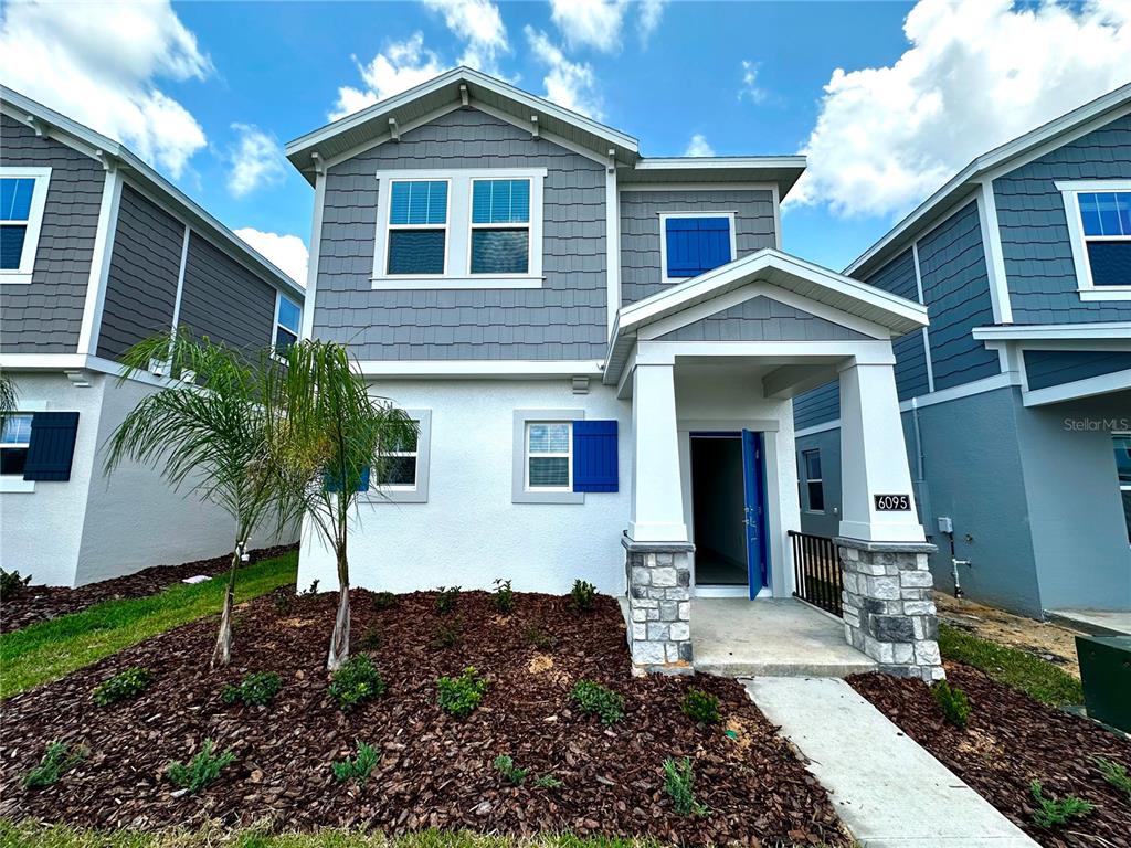 A two-story suburban house with gray siding, white stucco, and blue shutters — 6095 WELLBEING WAY, CLERMONT, FL