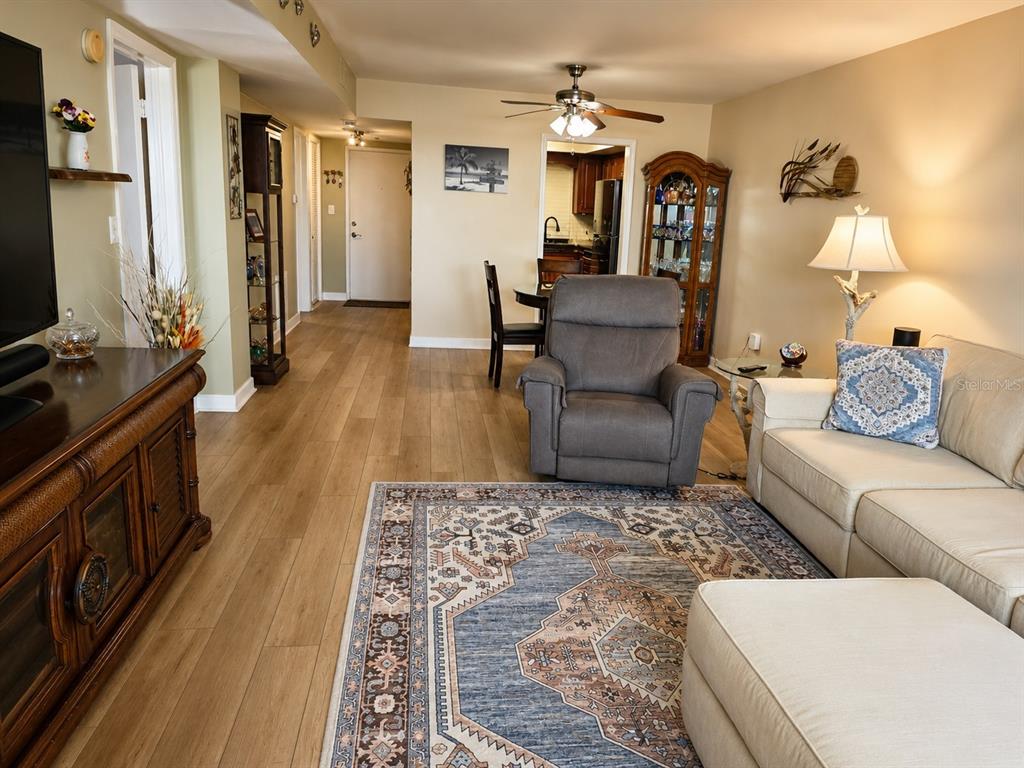 A living room features light wood flooring, a patterned area rug, and a beige sofa — 5130 BRITTANY DRIVE S UNIT 604, ST PETERSBURG, FL