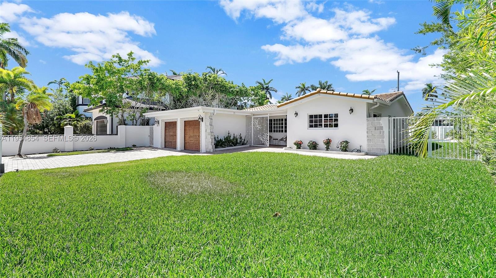 A white single-story house features a paved driveway, a two-car garage, and a large lawn — 1311 Pierce St, Hollywood FL 33019, HOLLYWOOD, FL