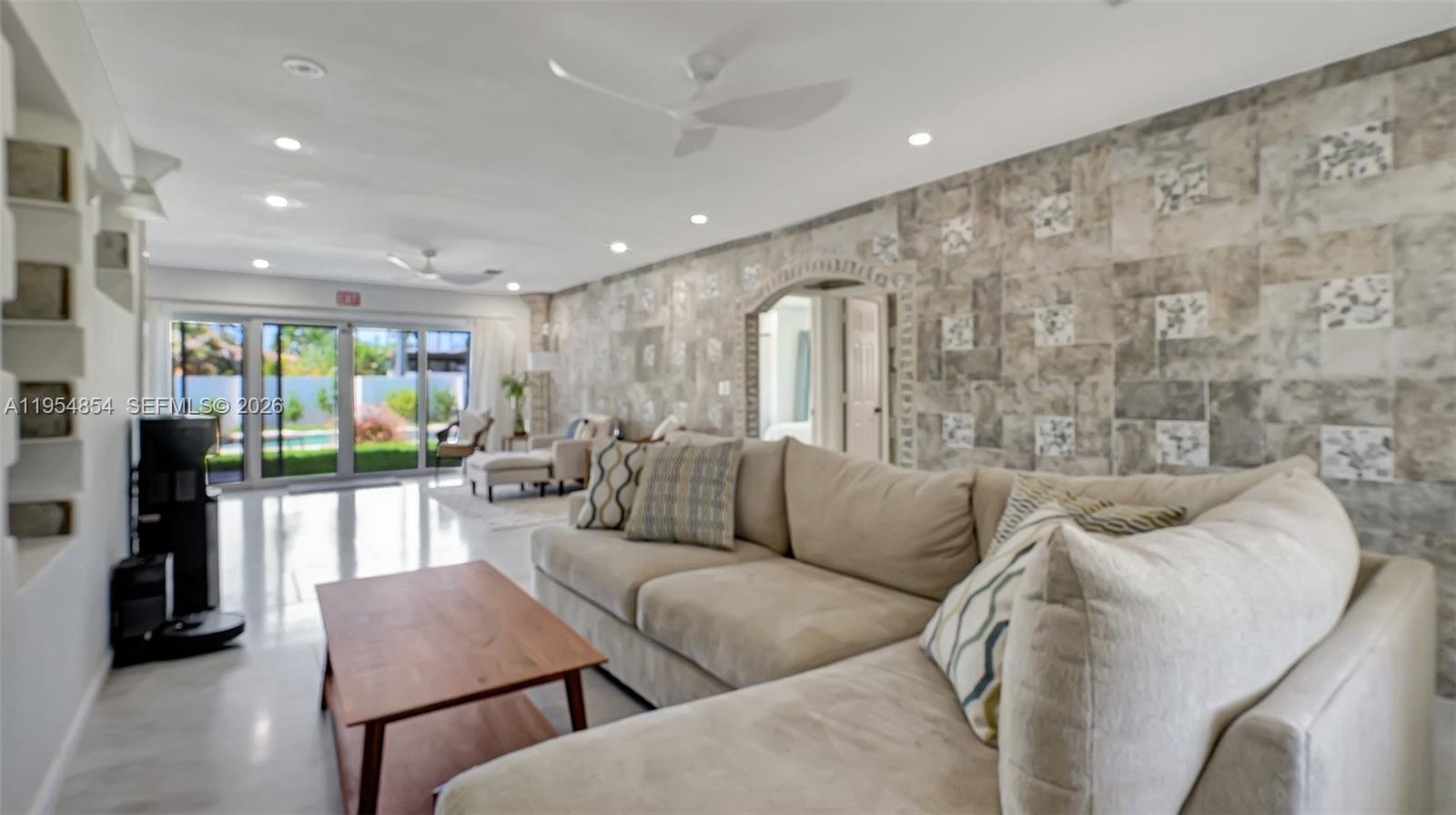 A living room features a large beige sectional sofa, a stone accent wall, and sliding doors — 1311 Pierce St, Hollywood FL 33019, HOLLYWOOD, FL