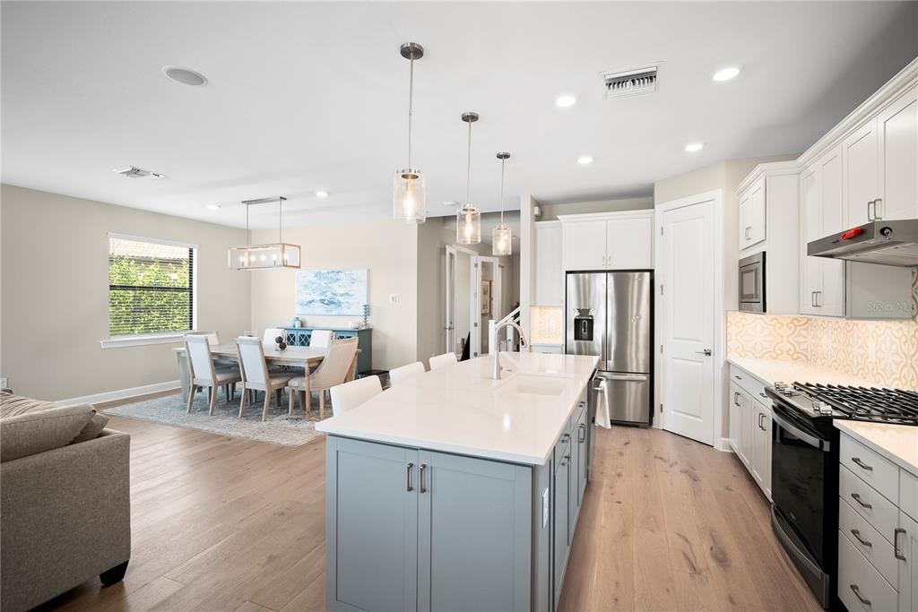 A kitchen with a gray island and white cabinets opens to a dining area — 12537 AQUA RESERVE COURT, FORT MYERS, FL