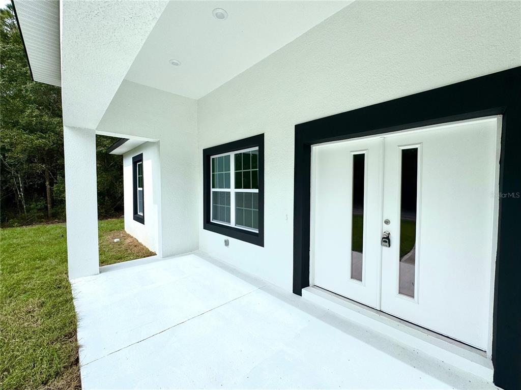 A white exterior wall features a double front door and a window with black trim — 9210 N HUNTER WAY, CITRUS SPRINGS, FL