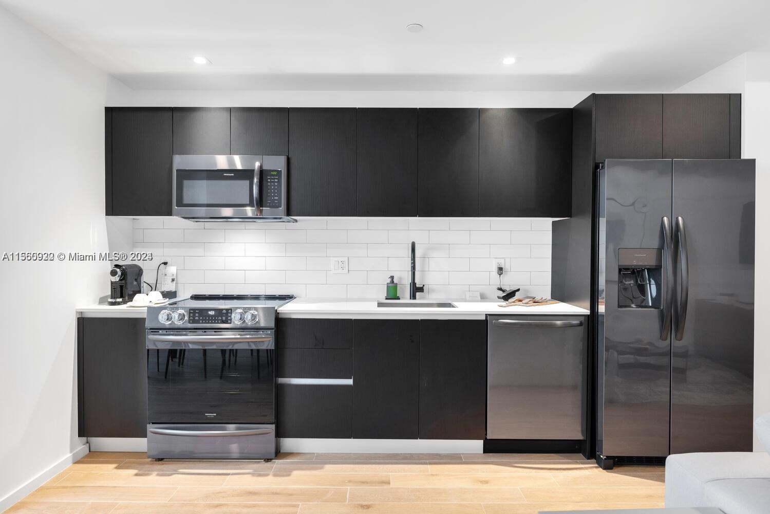 A modern kitchen features dark cabinetry, stainless steel appliances, and a white subway tile backsplash — 398 NE 5th St # 4708, Miami FL 33132, MIAMI, FL