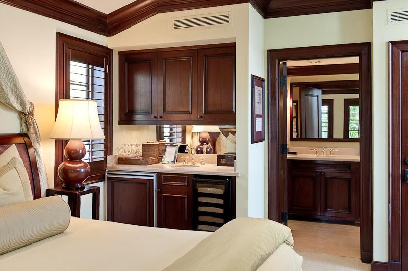 A bedroom featuring a wet bar, dark wood cabinetry, and an adjoining bathroom — 301 Australian Avenue # 306, Palm Beach FL 33480, PALM BEACH, FL