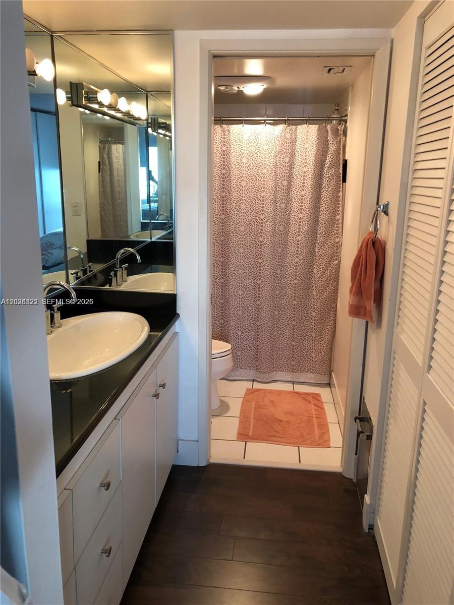 A bathroom features a white vanity with a black countertop, a mirror, and a shower — MIAMI, FL