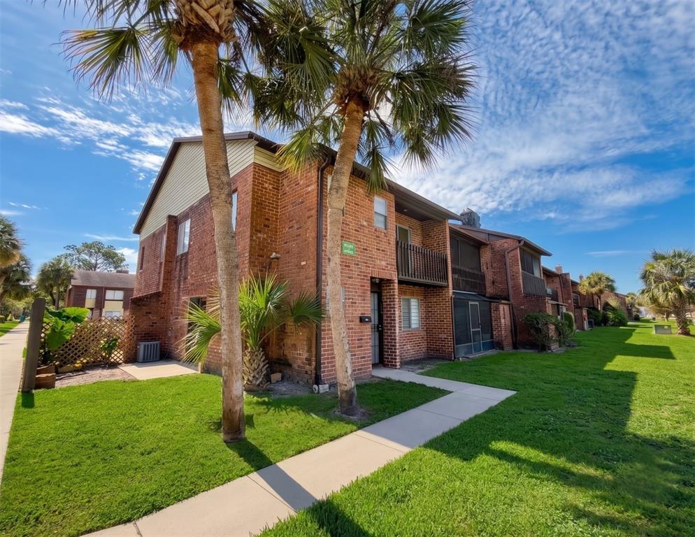 A two-story brick apartment building with palm trees and a concrete walkway on a lawn — 5100 PICADILLY CIRCUS UNIT 12, ORLANDO, FL
