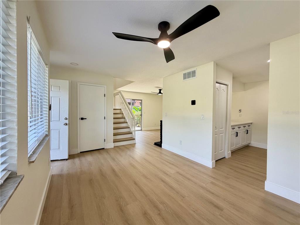 A bright living area features light wood-look flooring, a ceiling fan, and a staircase — 5100 PICADILLY CIRCUS UNIT 12, ORLANDO, FL