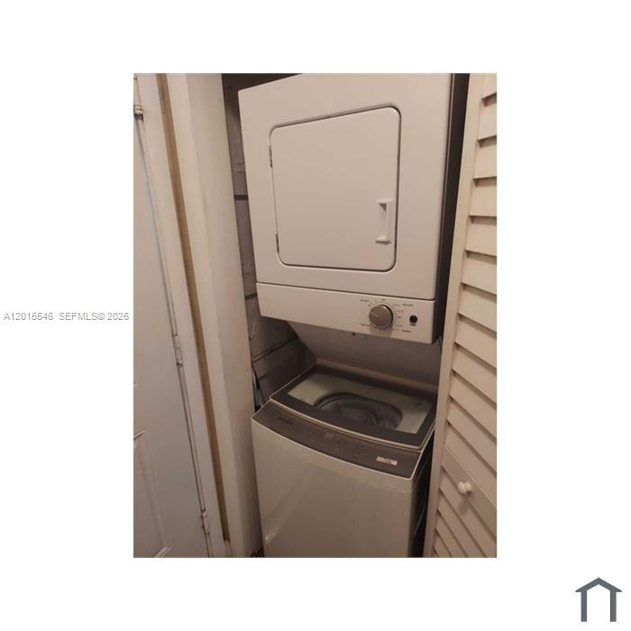 A white stacked washer and dryer unit is installed in a small laundry closet — 207 NE 141st St # 4, Miami FL 33161, MIAMI, FL