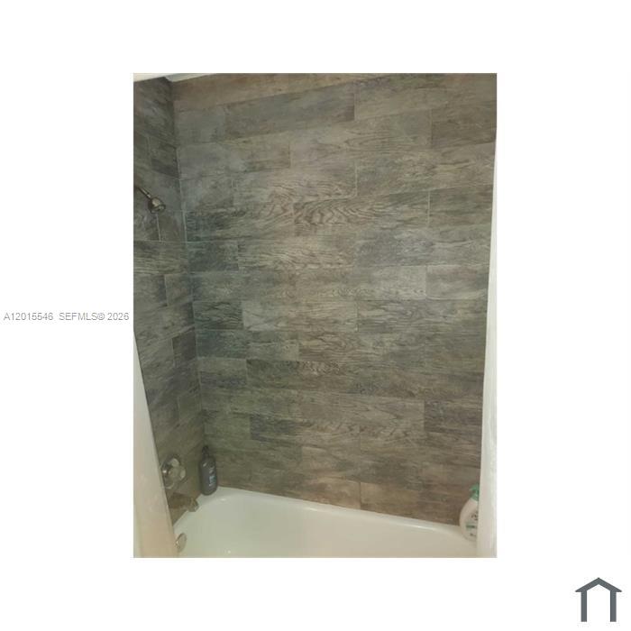 A bathroom features a white bathtub and walls covered in gray wood-look tile — 207 NE 141st St # 4, Miami FL 33161, MIAMI, FL