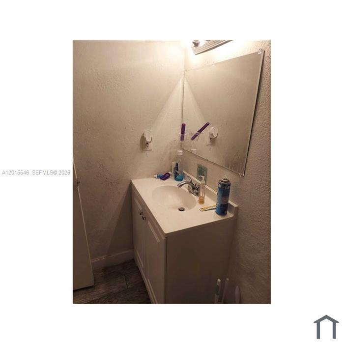 A bathroom vanity with a white sink, chrome faucet, and a wall-mounted mirror — 207 NE 141st St # 4, Miami FL 33161, MIAMI, FL