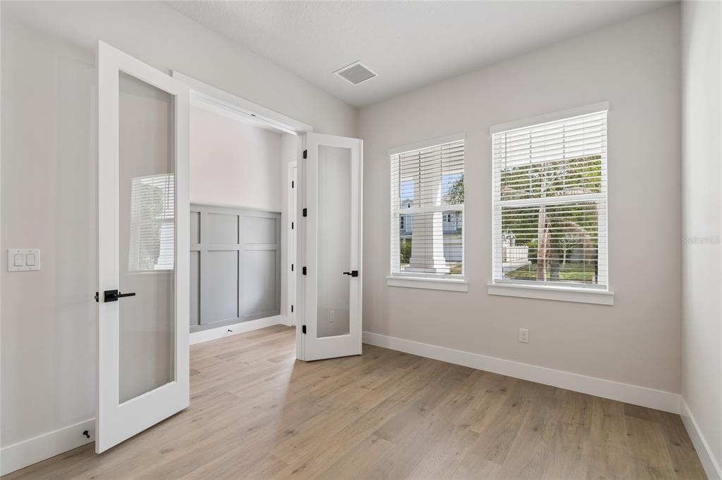 A room with light wood flooring, white walls, and French doors leading to an office space — 3711 W DE LEON STREET, TAMPA, FL