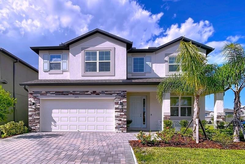 A two-story house with a stone-accented facade, a two-car garage, and a paved driveway — 2450 SUNNY PEBBLE LOOP, ZEPHYRHILLS, FL
