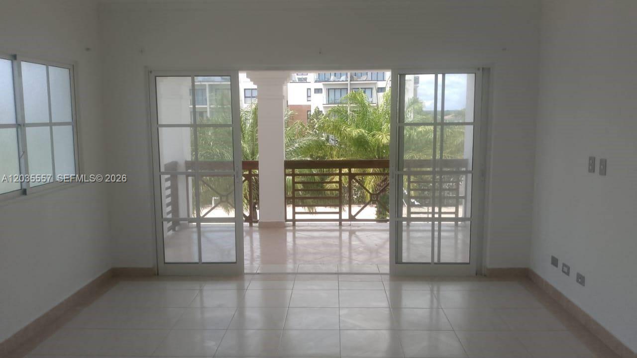 An empty room with white walls, tile floors, and sliding glass doors leading to a balcony — 1 cap cana # 0, FL