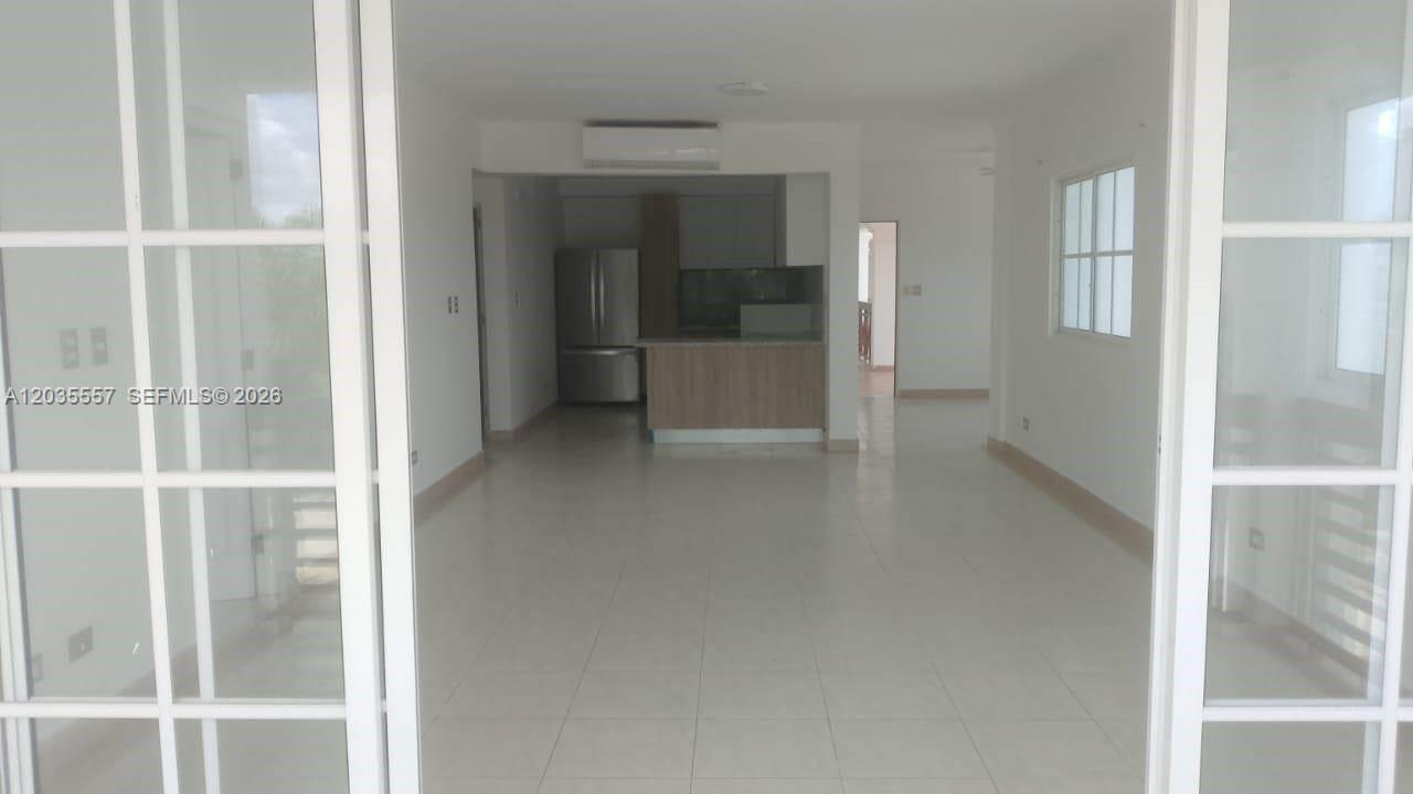 An interior view shows a tiled living area leading to an open kitchen with cabinetry — 1 cap cana # 0, FL