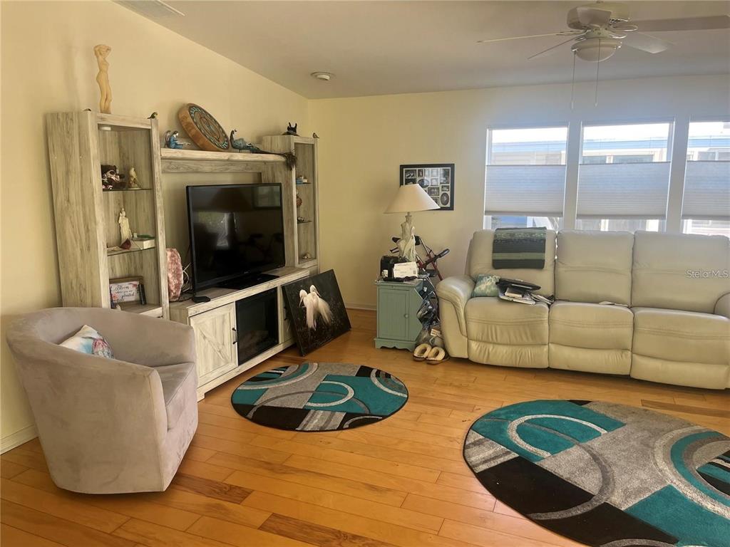 A living room features light wood flooring, a white entertainment center, and a light-colored sofa — 3364 GOLDA CIRCLE, NORTH FORT MYERS, FL