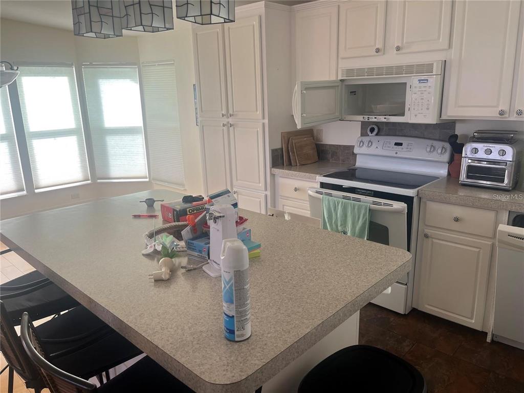 A kitchen features white cabinets, a large island with a countertop, and white appliances — 3364 GOLDA CIRCLE, NORTH FORT MYERS, FL