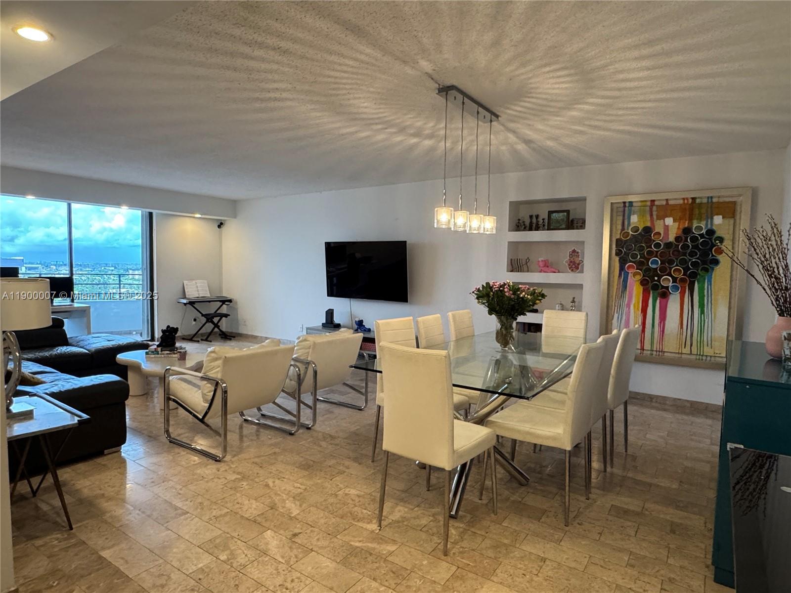 A spacious open-concept living and dining area features tile flooring, modern furniture, and floor-to-ceiling windows — 600 Three Islands Blvd # 1206, Hallandale Beach FL 33009, HALLANDALE BEACH, FL