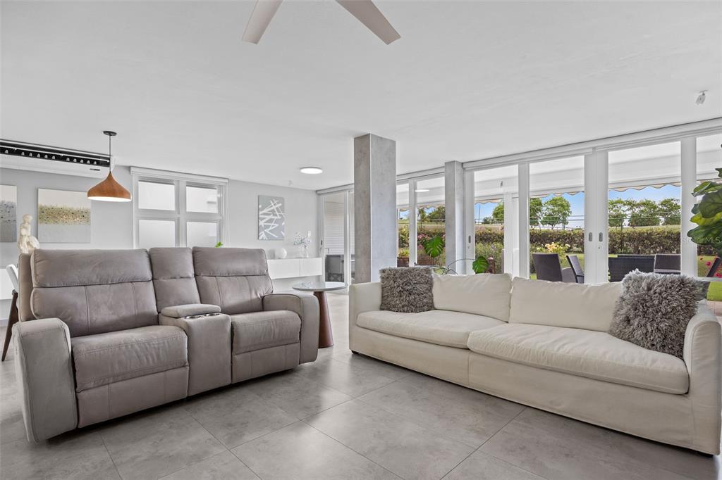A living room features a gray reclining sofa, a white sofa, and large glass sliding doors — M1 COSTA DORADA UNIT M1, DORADO, PR