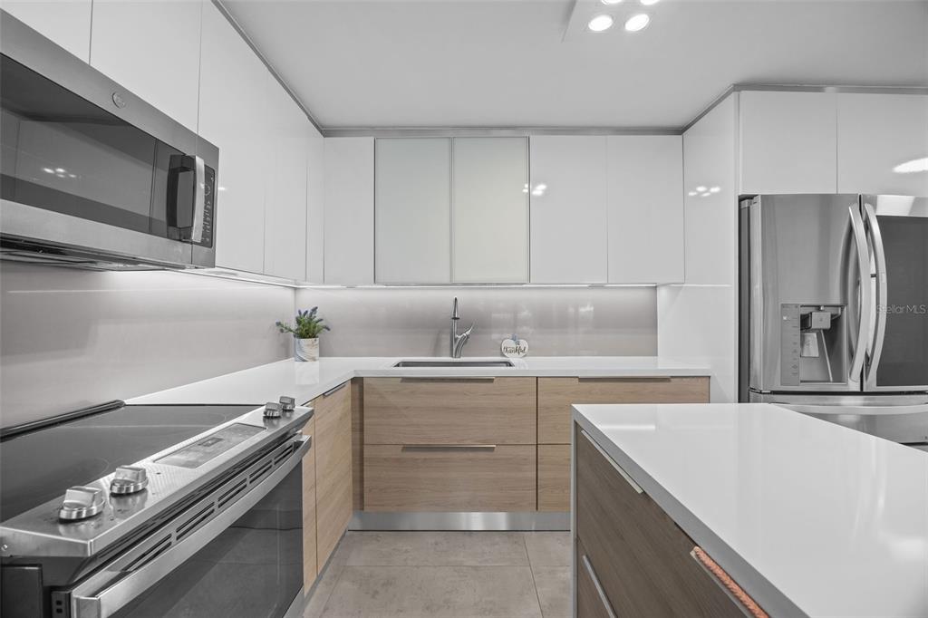 A modern kitchen features white upper cabinets, wood-tone lower cabinets, and stainless steel appliances — M1 COSTA DORADA UNIT M1, DORADO, PR