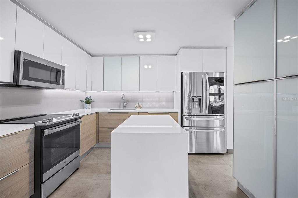 A modern kitchen features white upper cabinets, wood-tone lower cabinets, a central island, and appliances — M1 COSTA DORADA UNIT M1, DORADO, PR