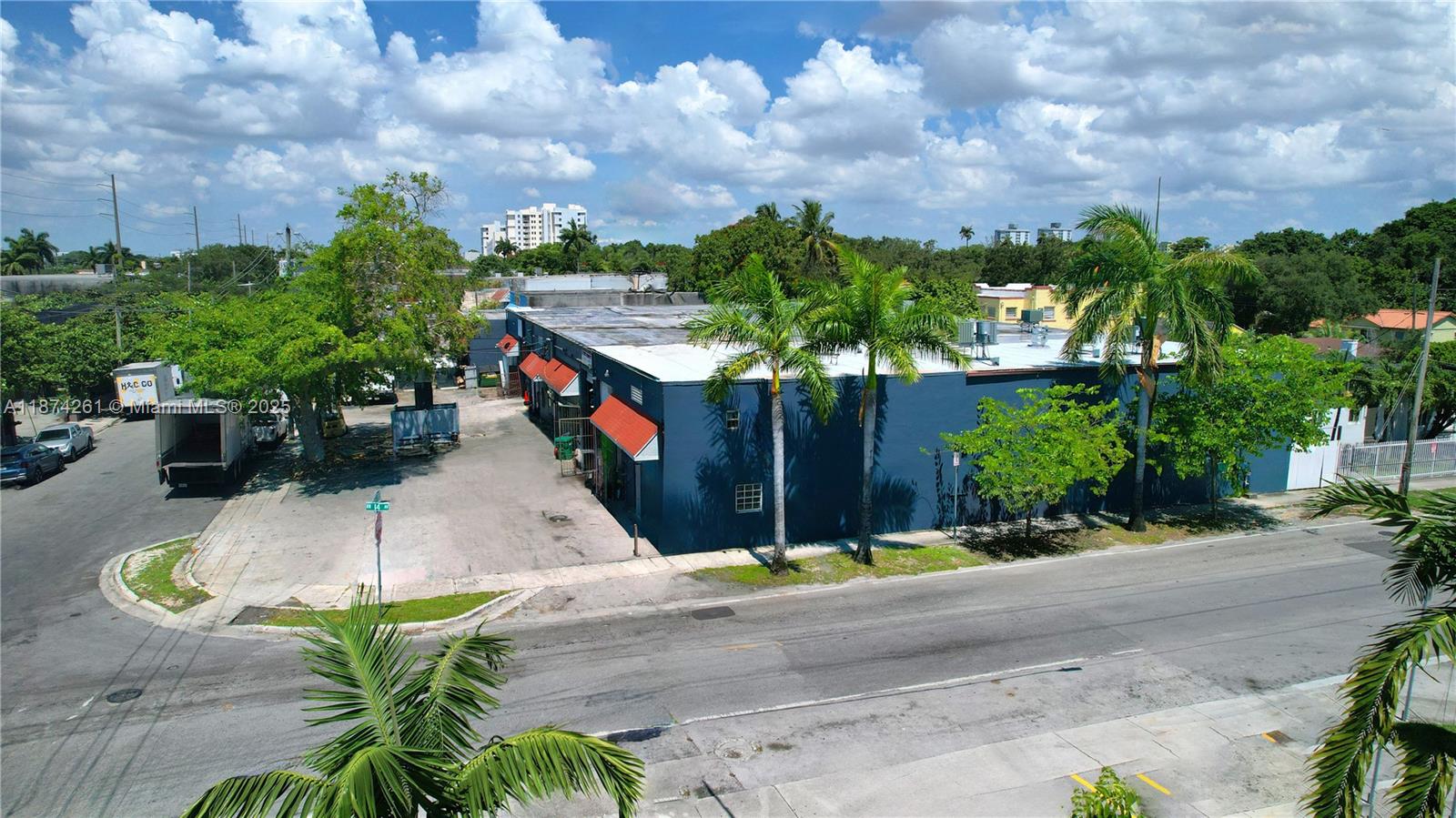 An aerial view shows a blue commercial building with orange awnings and surrounding palm trees — 1401 NW 23rd St, Miami FL 33142, MIAMI, FL